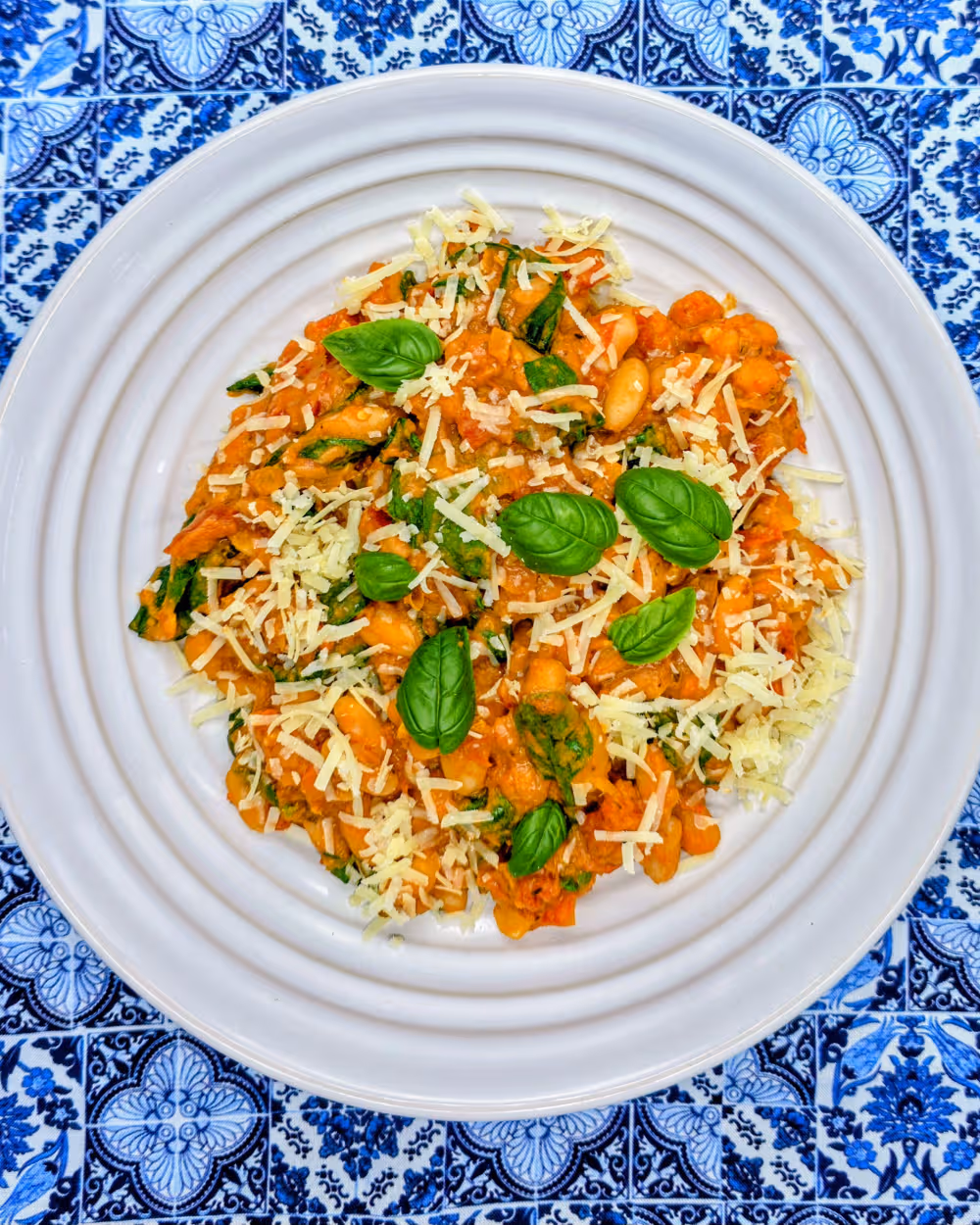 Plated Marry Me Beans garnished with grated parmesan and fresh basil leaves.