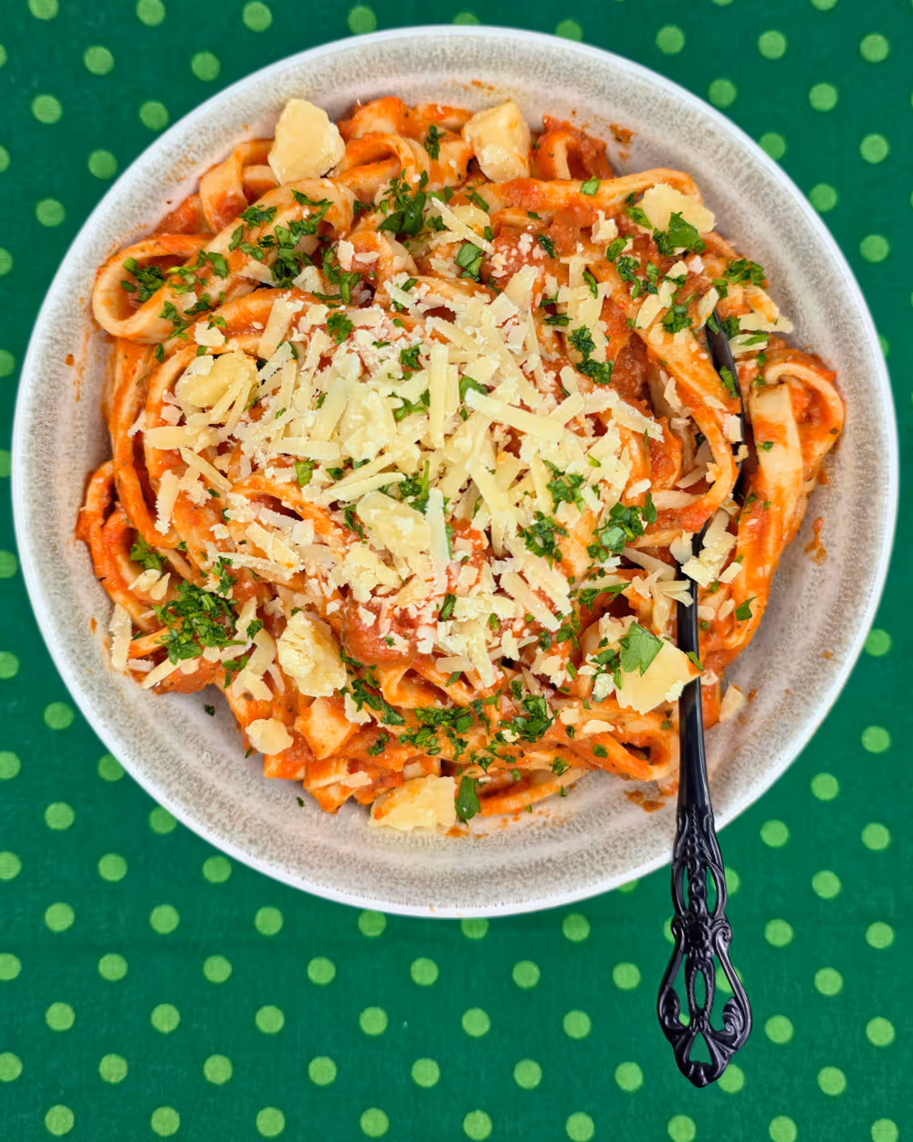 Ratatouille Pasta Sauce tossed through cooked, homemade pasta and topped with freshly grated parmesan cheese. Served in a bowl with a fork.